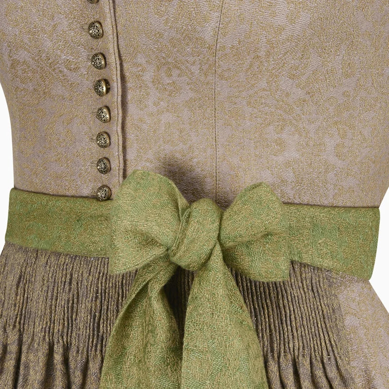 Close-up of a traditional outfit with a green ribbon and beige patterned fabric.