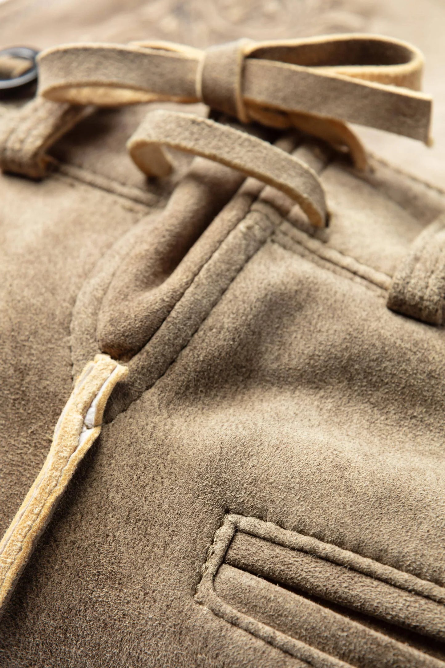 Close-up of a brown coat with a belt and button details