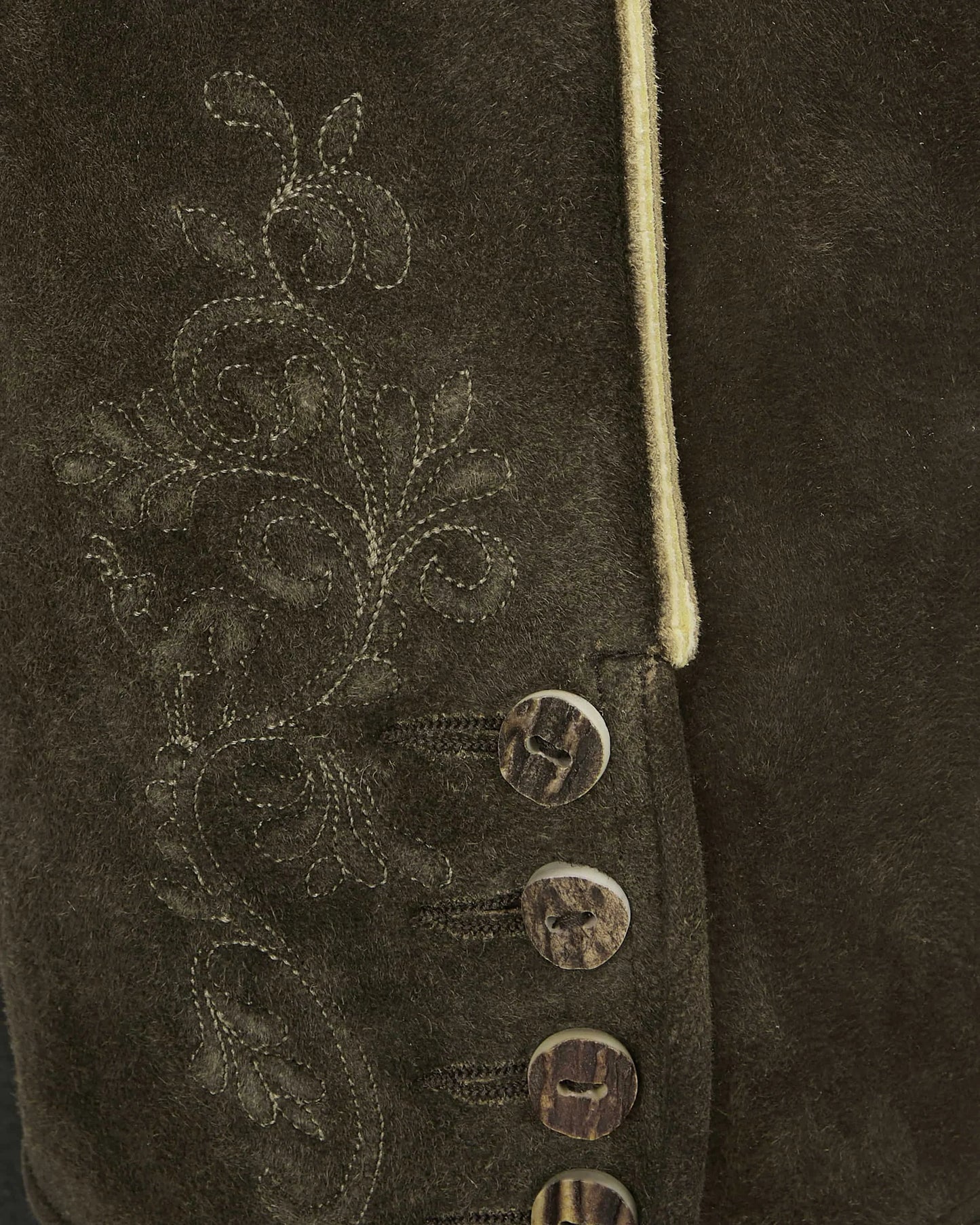 Close-up of a brown suede jacket with floral embroidery and buttons.