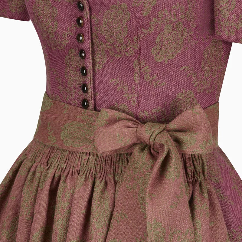Close-up of a pink dress with a patterned design and a bow detail on a white background