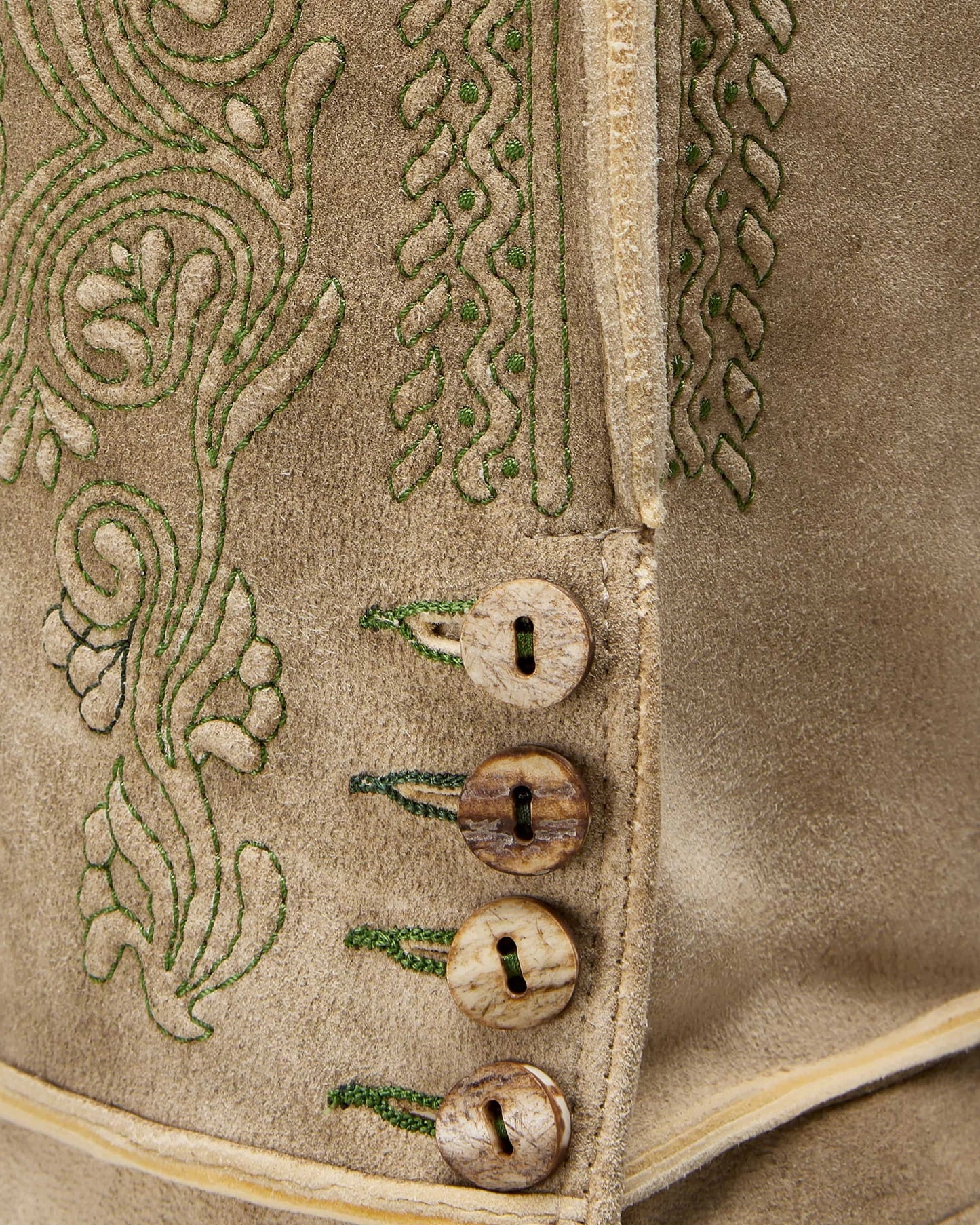 Close-up of a textured fabric with embroidered patterns and buttons.