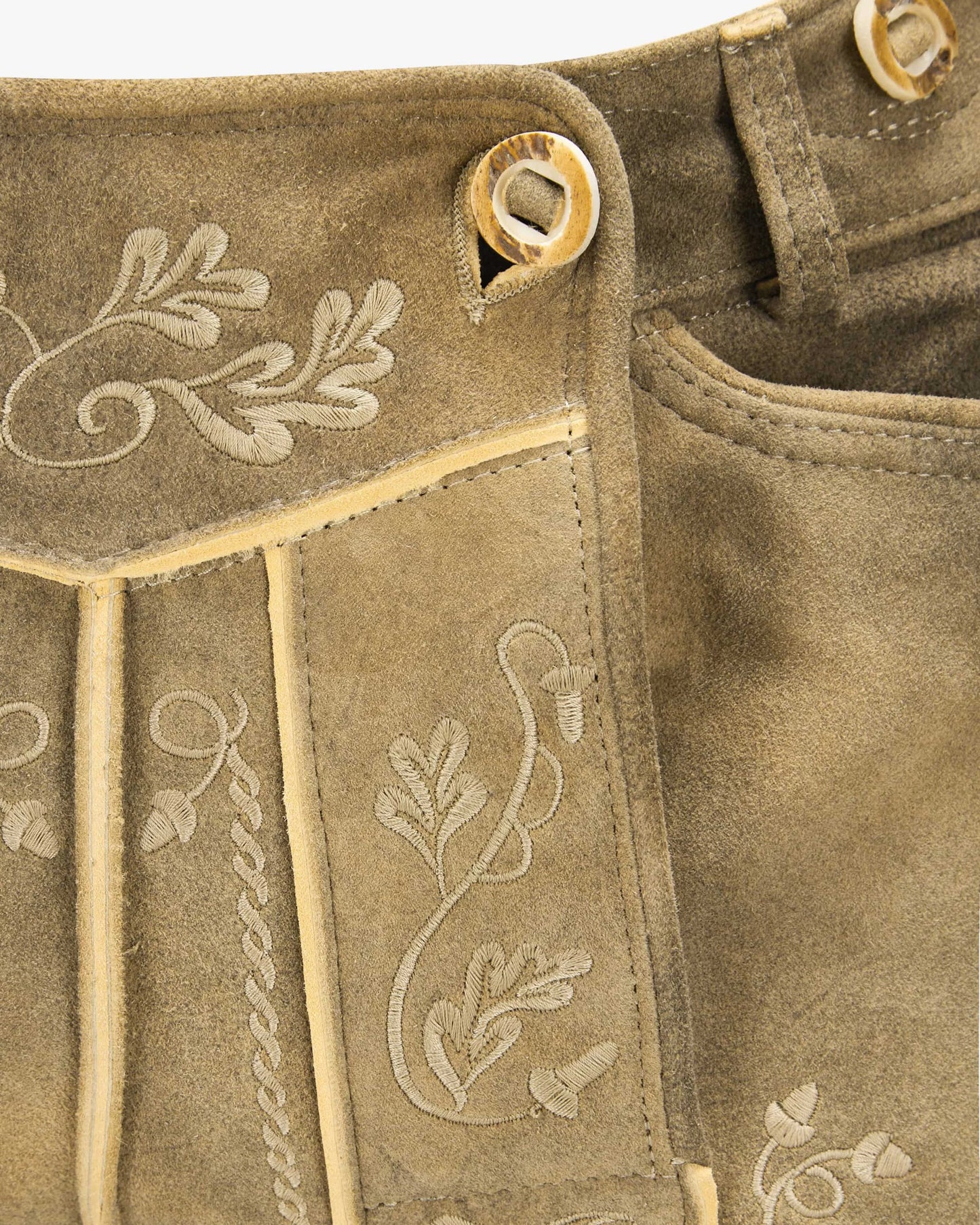 Close-up of brown fabric with embroidered floral patterns and button details.