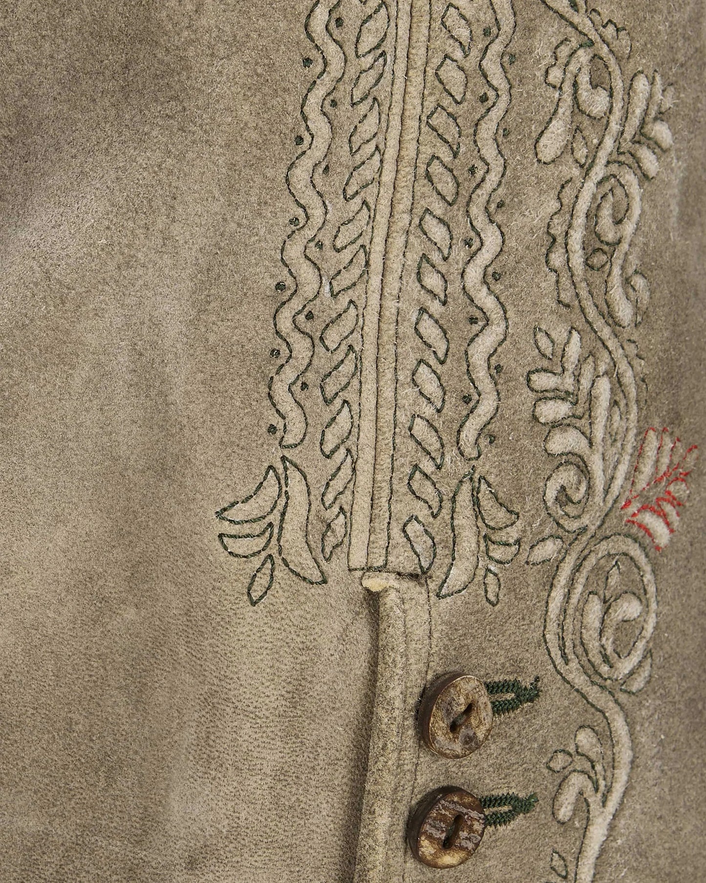 Close-up of embroidered fabric with intricate patterns on a beige background