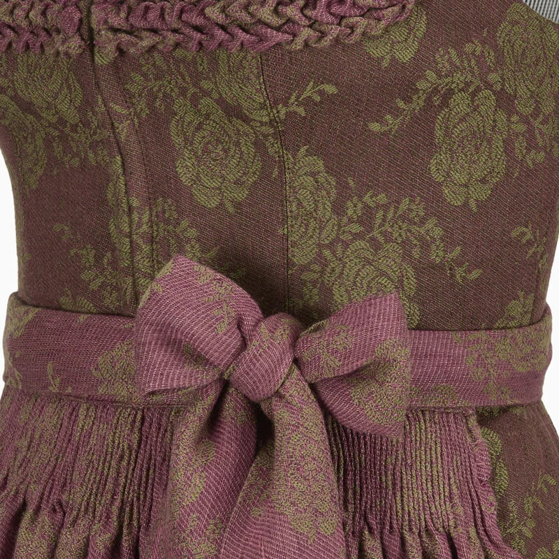 Close-up of a patterned dirndl dress with a bow detail on a brown background