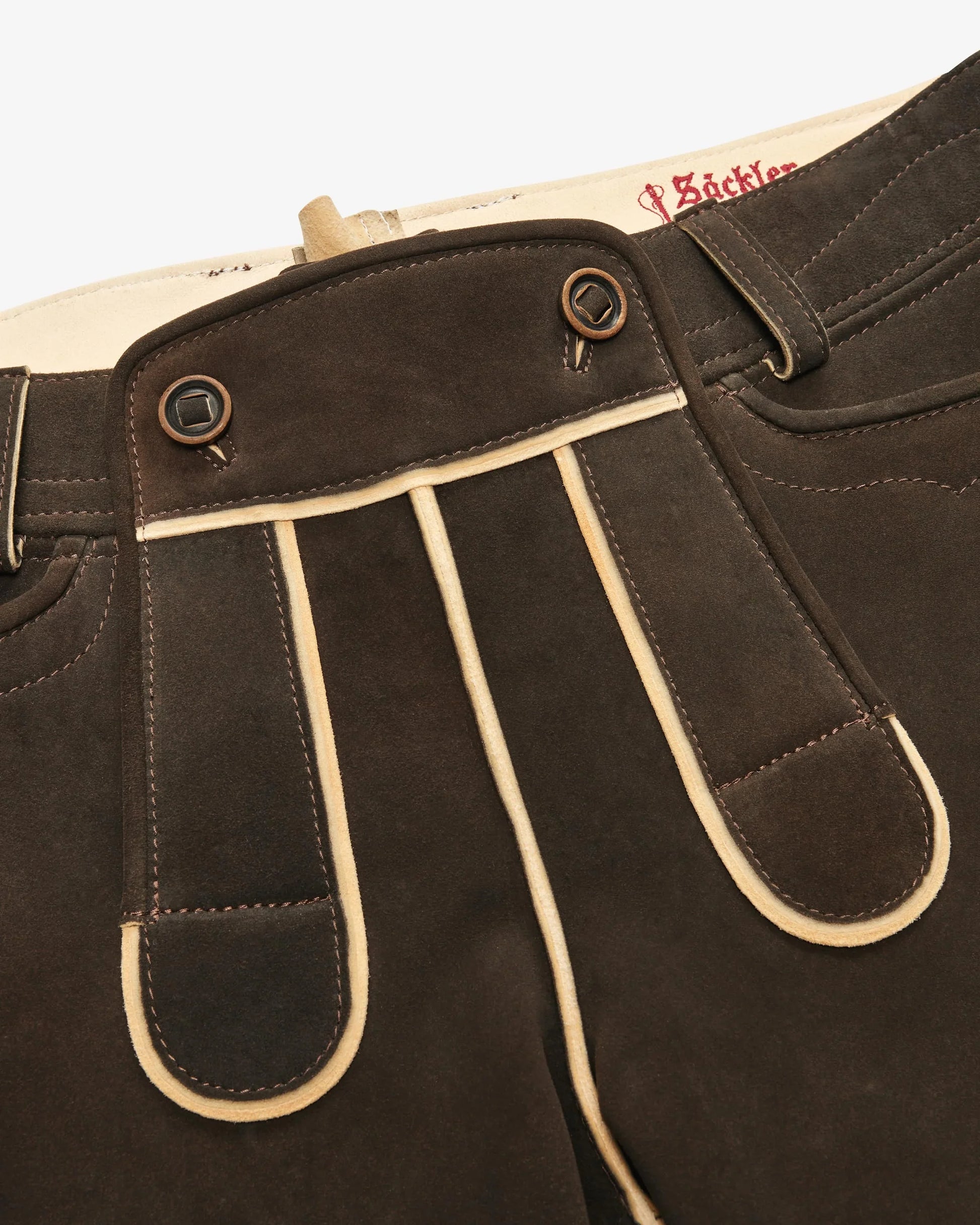 Brown leather pants with white stitching on a beige background