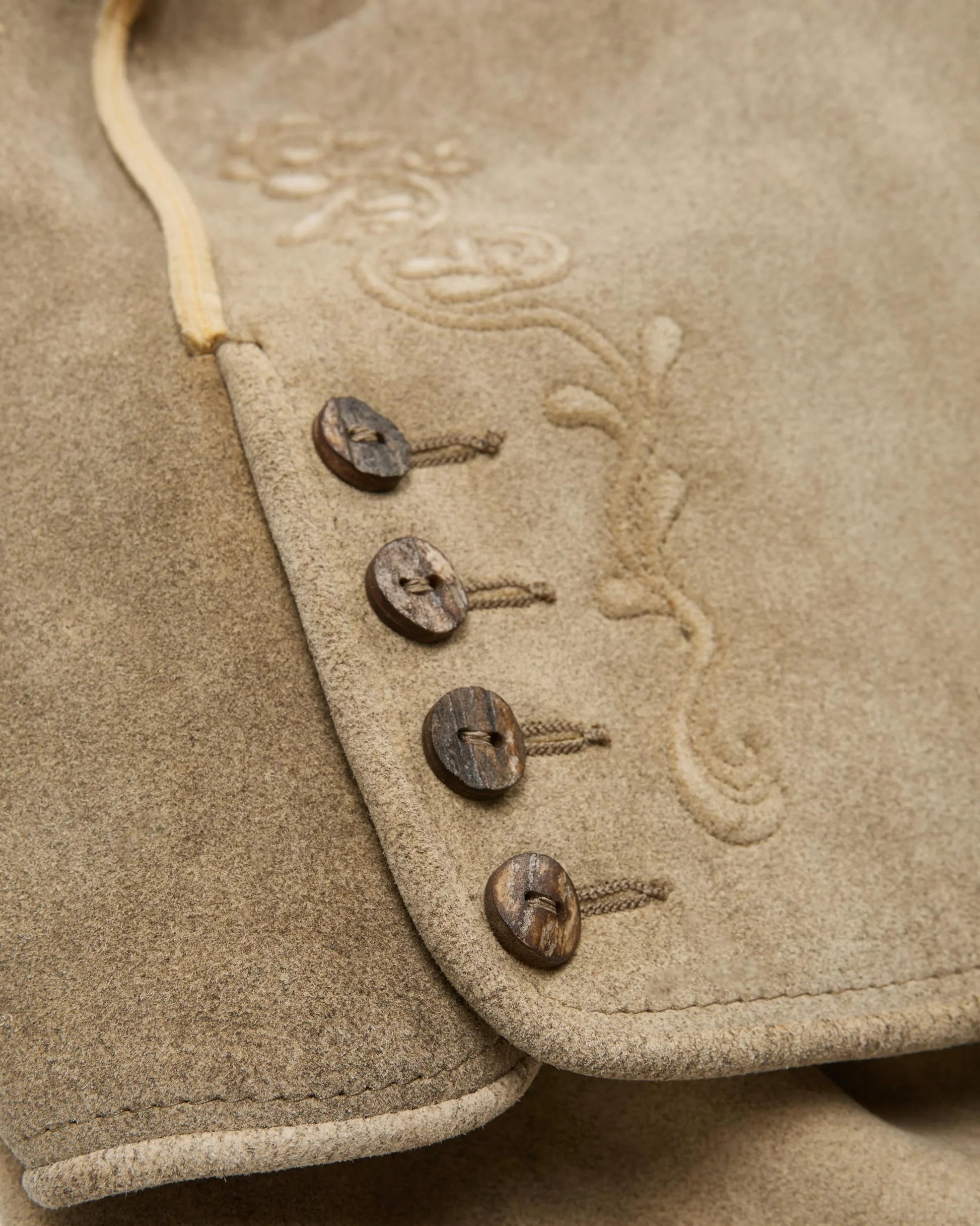Close-up of a textured fabric surface with embroidered designs and wooden buttons.