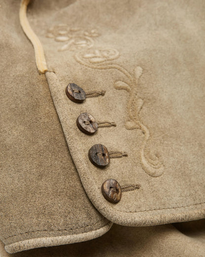 Close-up of a textured fabric surface with embroidered designs and wooden buttons.