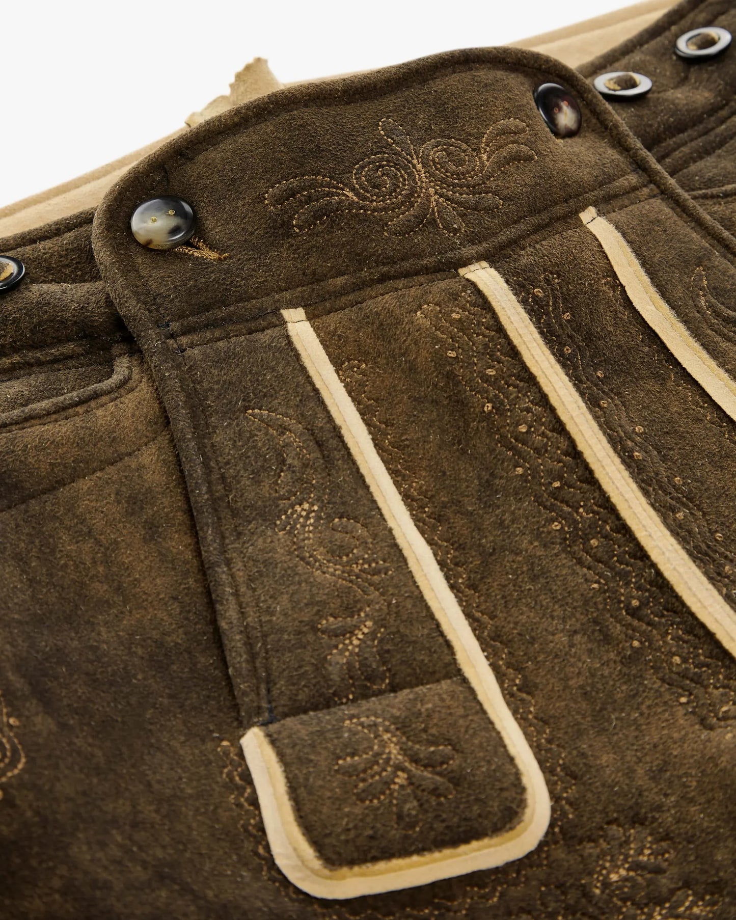Close-up of brown leather bag with decorative stitching and buttons.