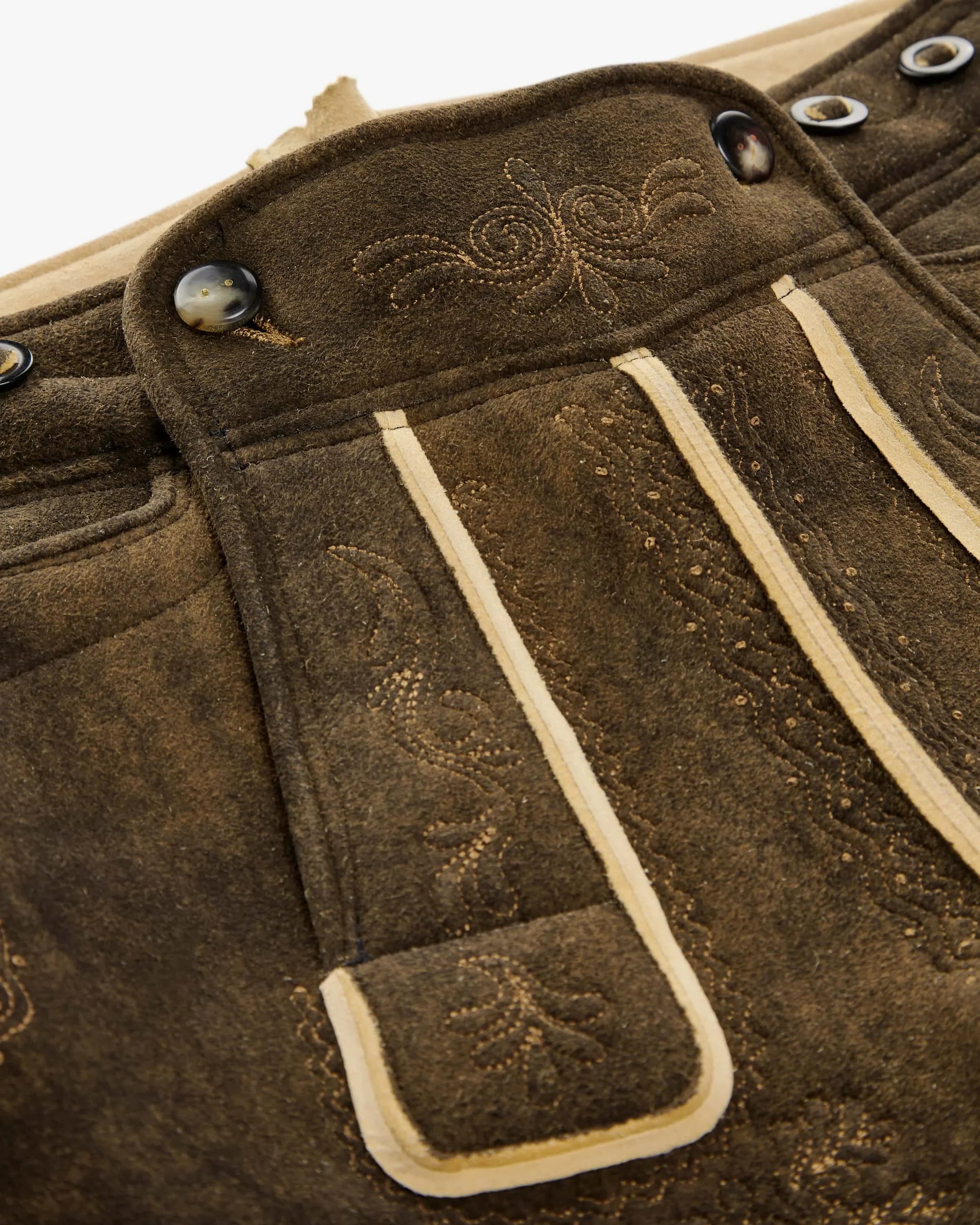 Close-up of brown leather bag with decorative stitching and buttons.