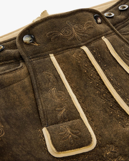 Close-up of brown leather bag with decorative stitching and buttons.