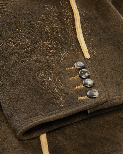 Close-up of a brown textured fabric with embroidered patterns and buttons.