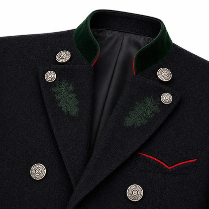Close-up of a dark wool coat with a green velvet peak collar, silver decorative buttons, green embroidered leaf motifs on the lapels, and red piping detail.