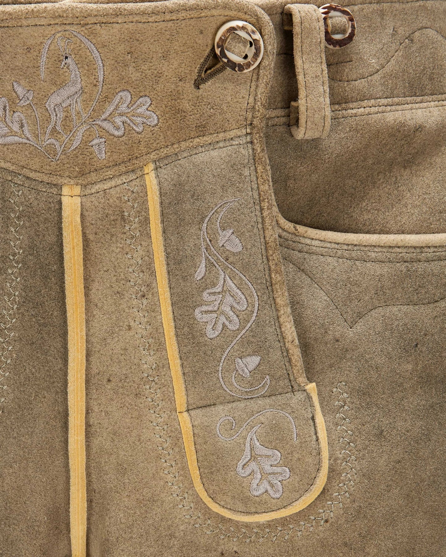 Close-up of brown leather pants with embroidery and button details