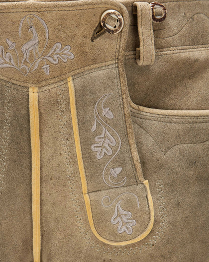 Close-up of brown leather pants with embroidery and button details