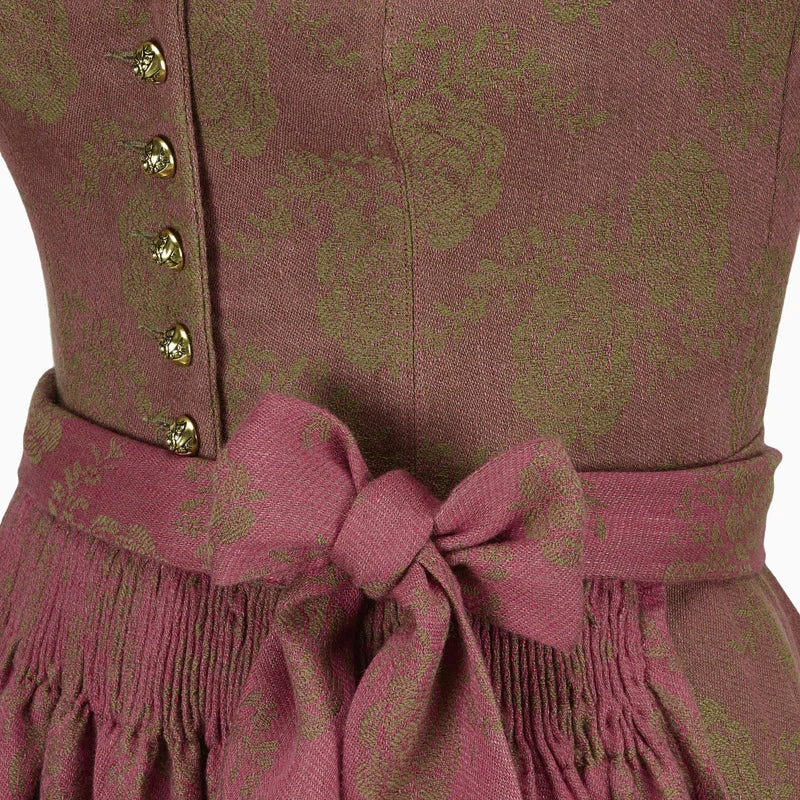 Close-up of a patterned dirndl dress with a belt and buttons on a white background