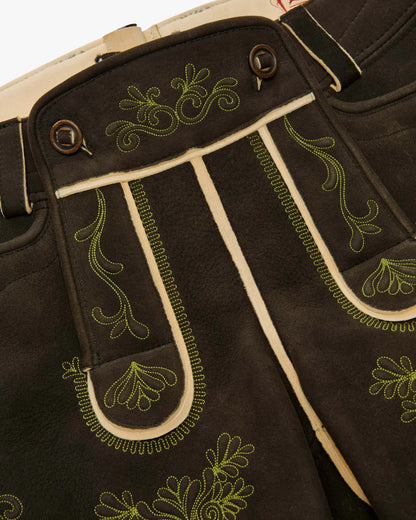 Close-up of black pants with green embroidery on a beige background