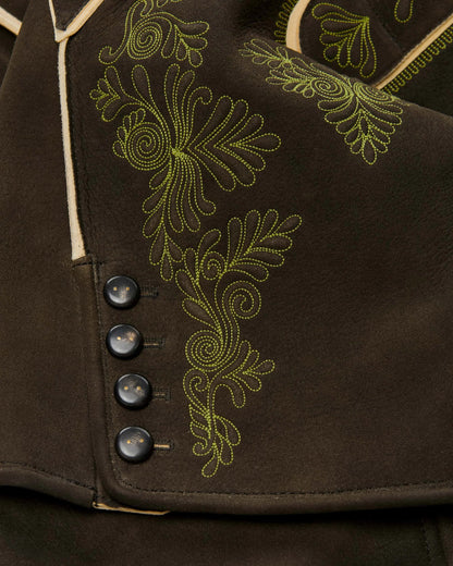 Close-up of a brown garment with green embroidery and buttons.