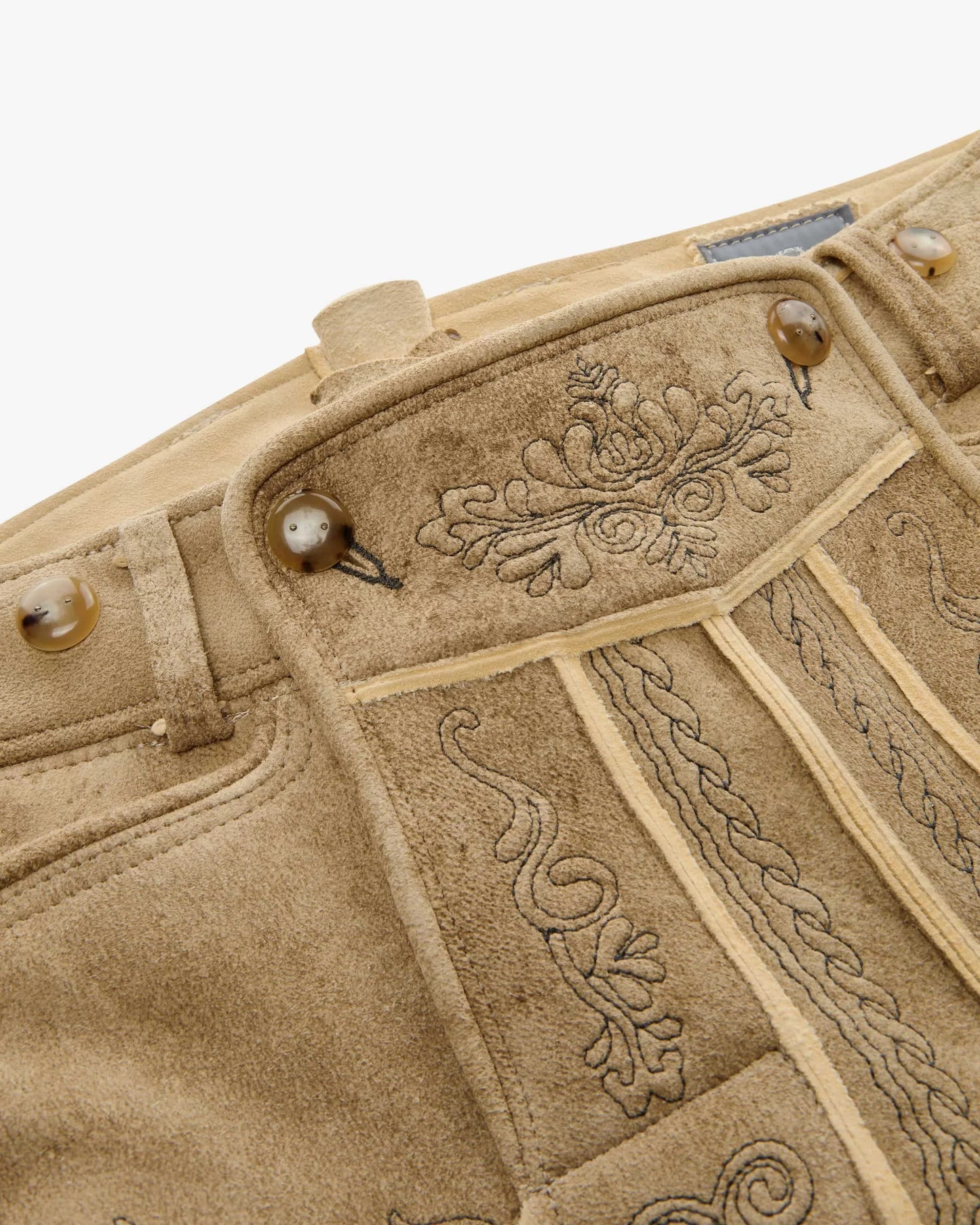 Close-up of beige fabric with intricate embroidery on a white background