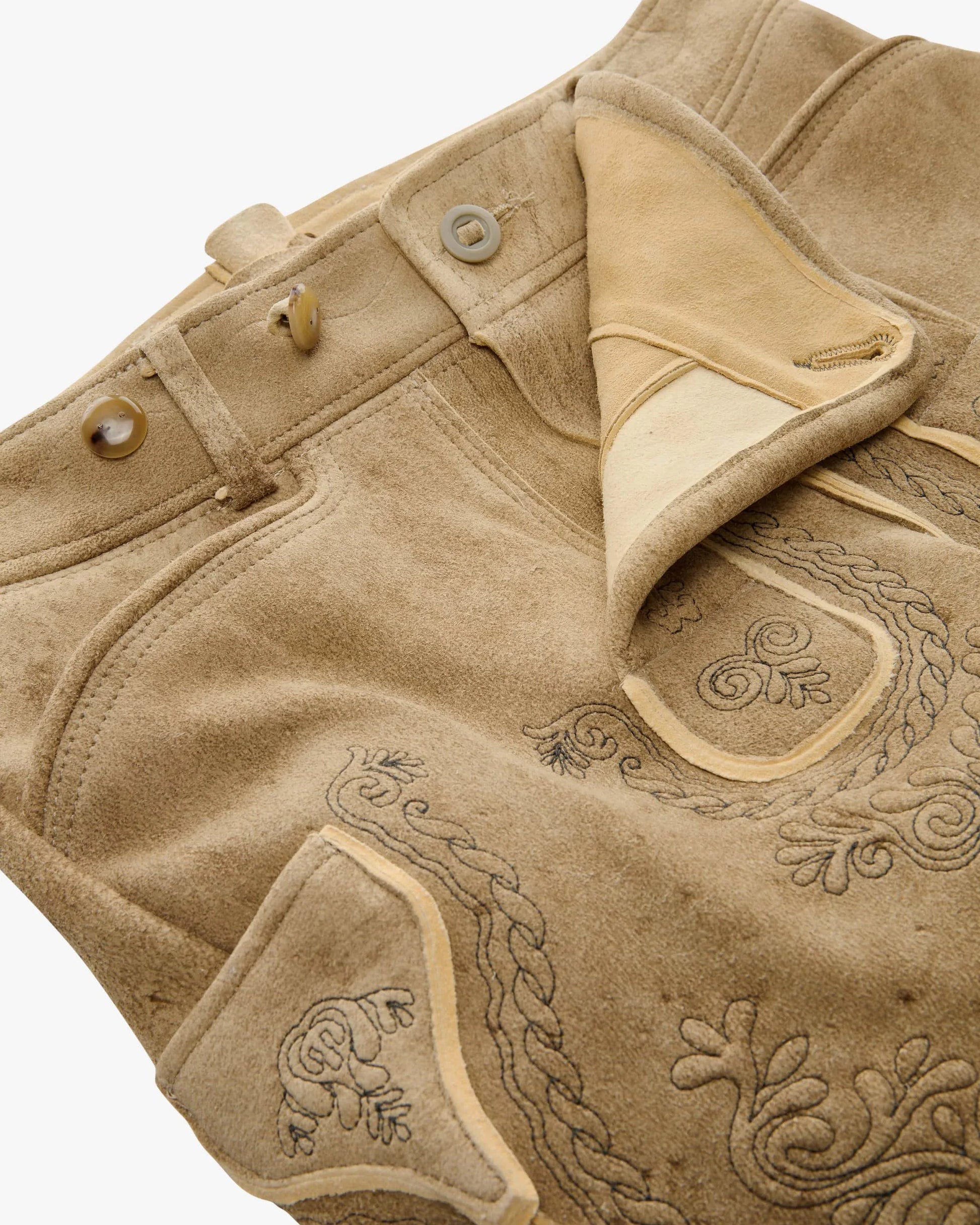 Close-up of a brown leather jacket with intricate embroidery on a white background