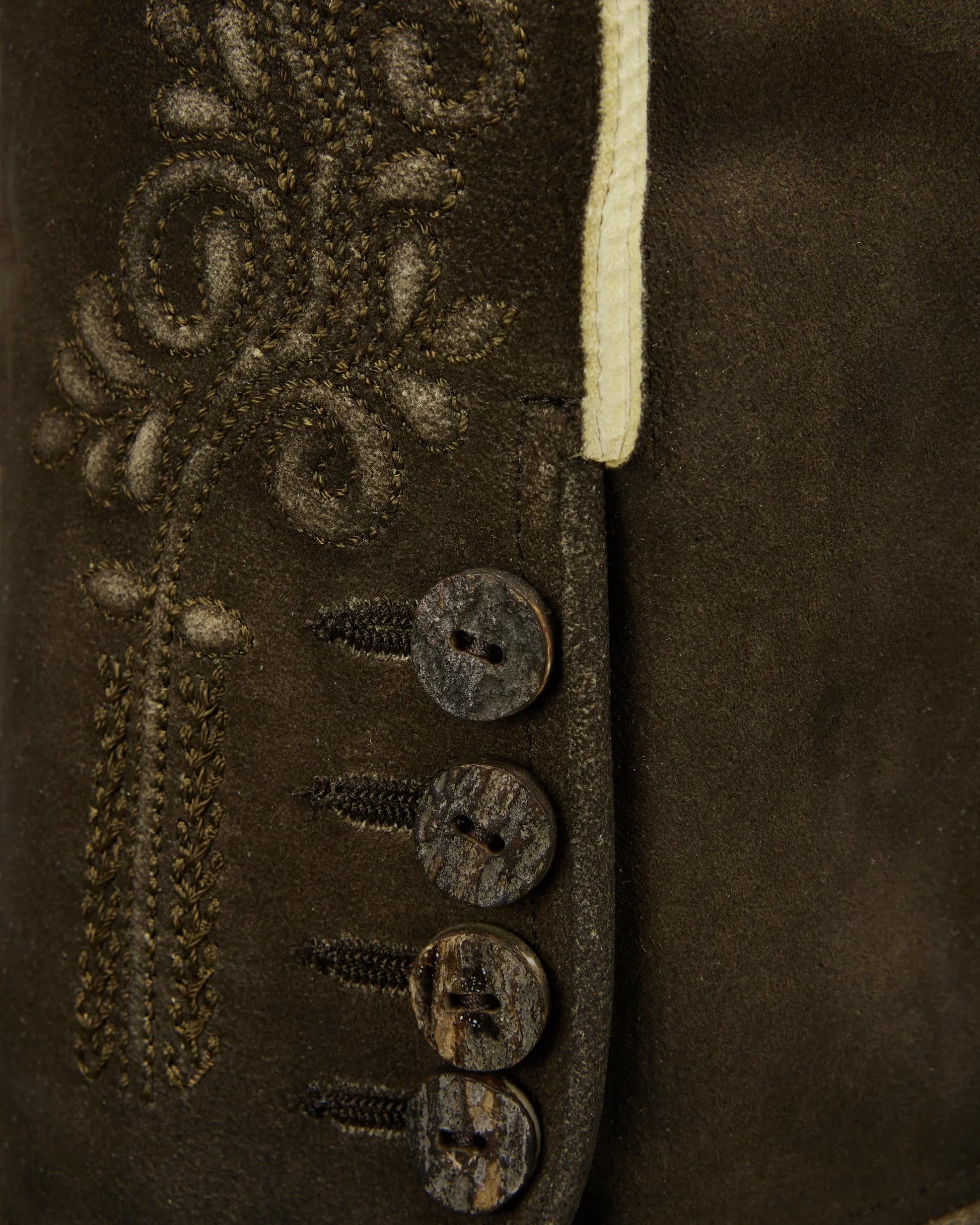 Close-up of a brown leather jacket with decorative buttons and stitching.