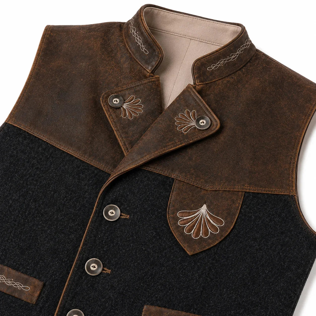 A close-up of a rustic brown and black vest with a high collar, button closure, and decorative shell embroidery on a white background.