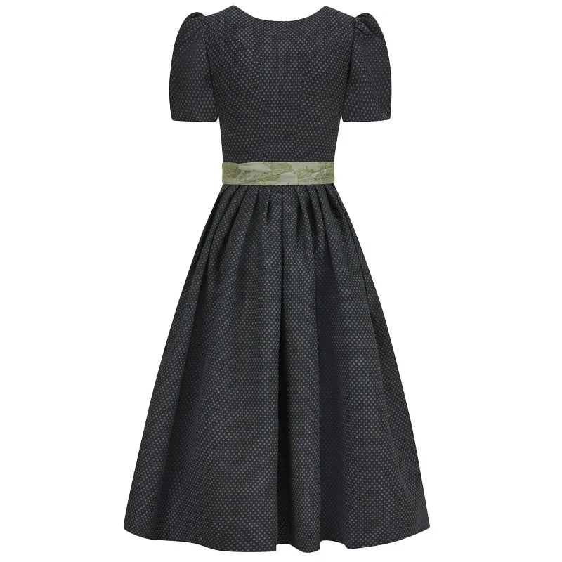Black polka dot dirndl dress with a green belt on a white background 