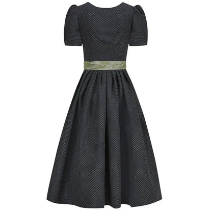 Black polka dot dirndl dress with a green belt on a white background 