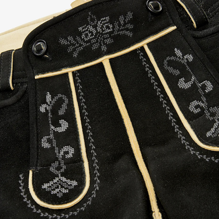 Close-up of black pants with white embroidery on a beige background