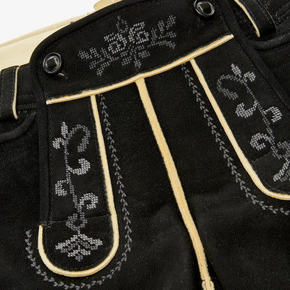 Close-up of black pants with white embroidery on a beige background