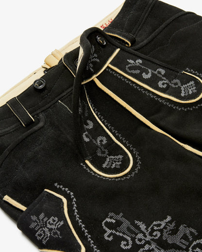 Close-up of black pants with decorative white stitching on a white background