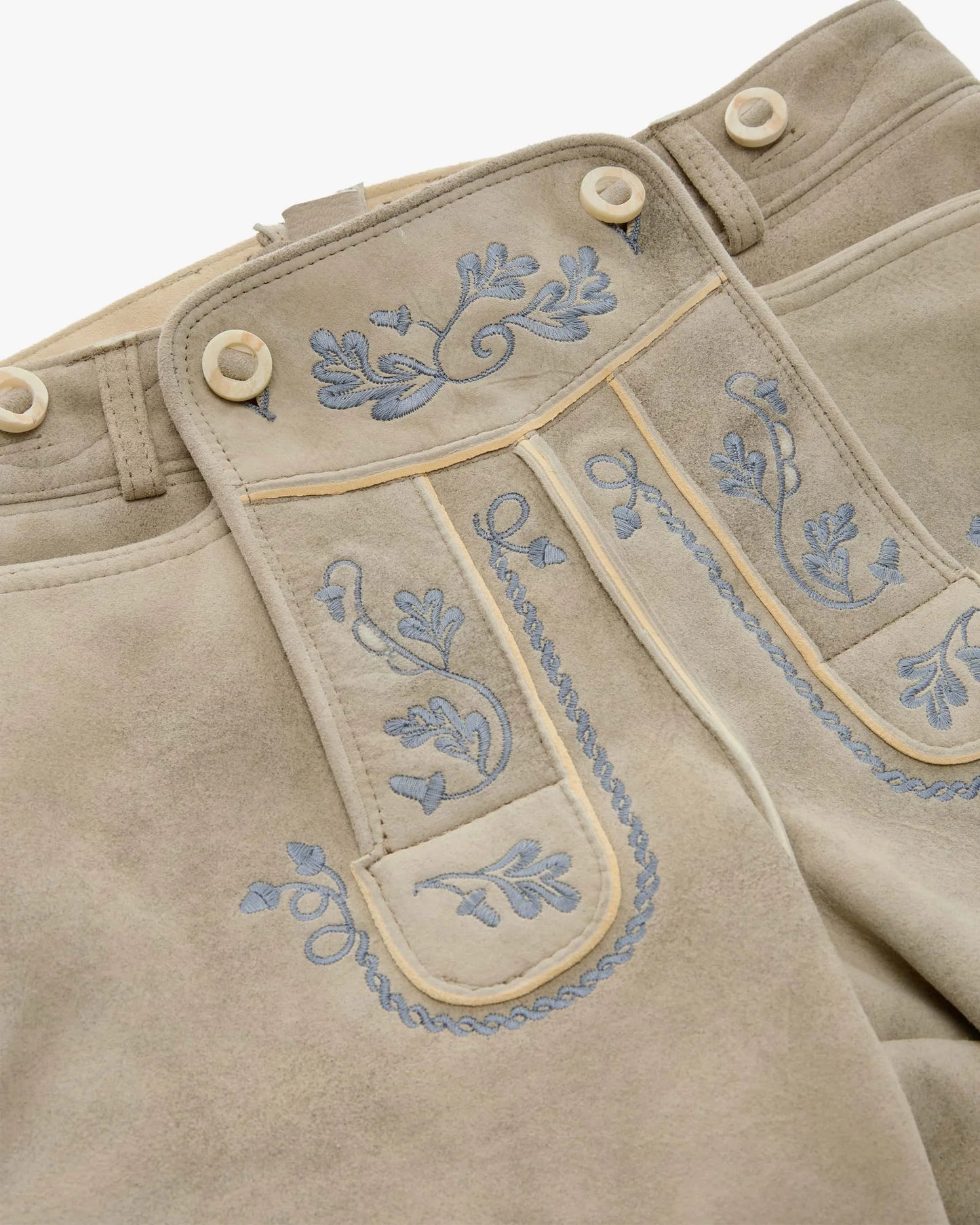 Beige pants with blue floral embroidery on a white background