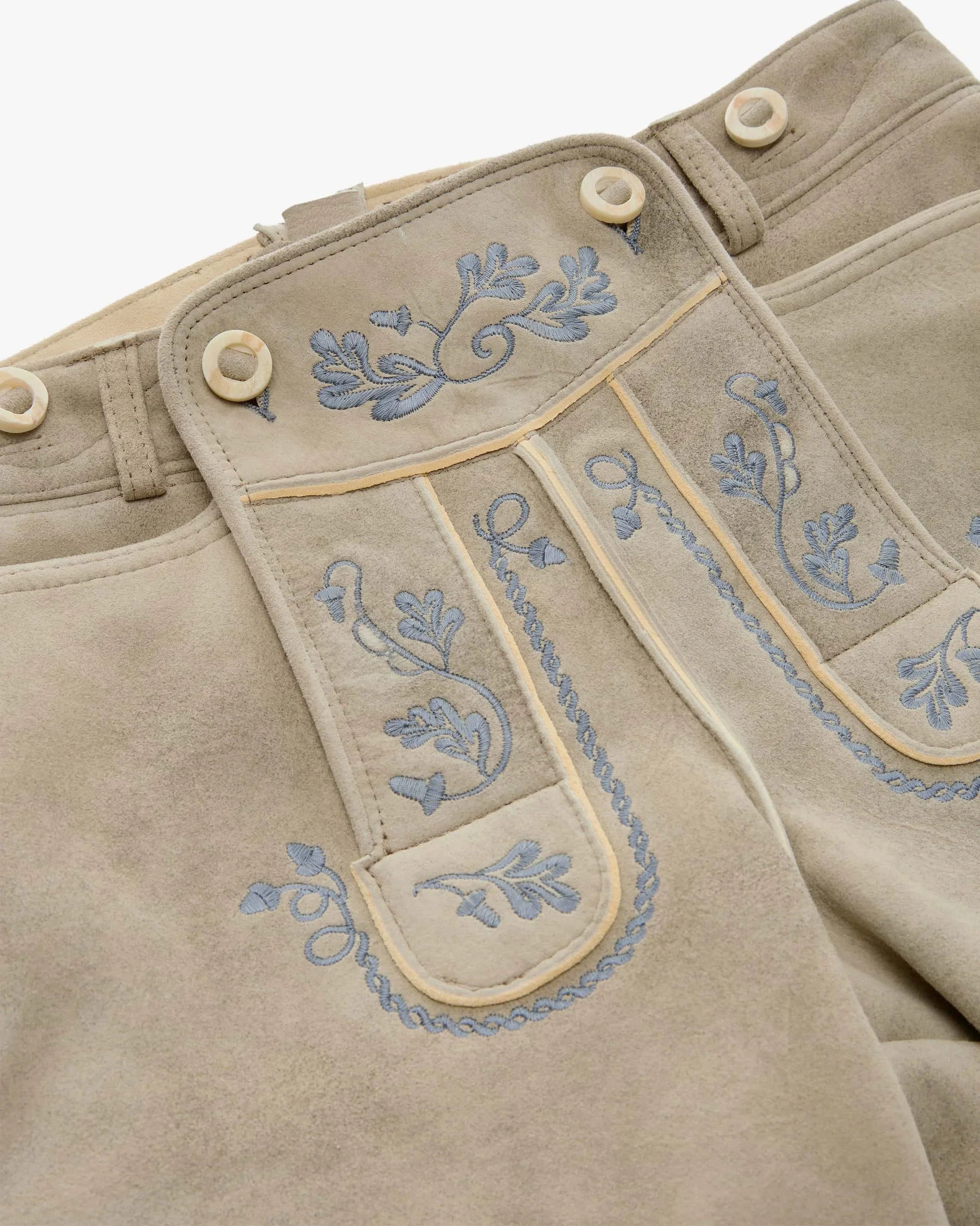 Beige pants with blue floral embroidery on a white background