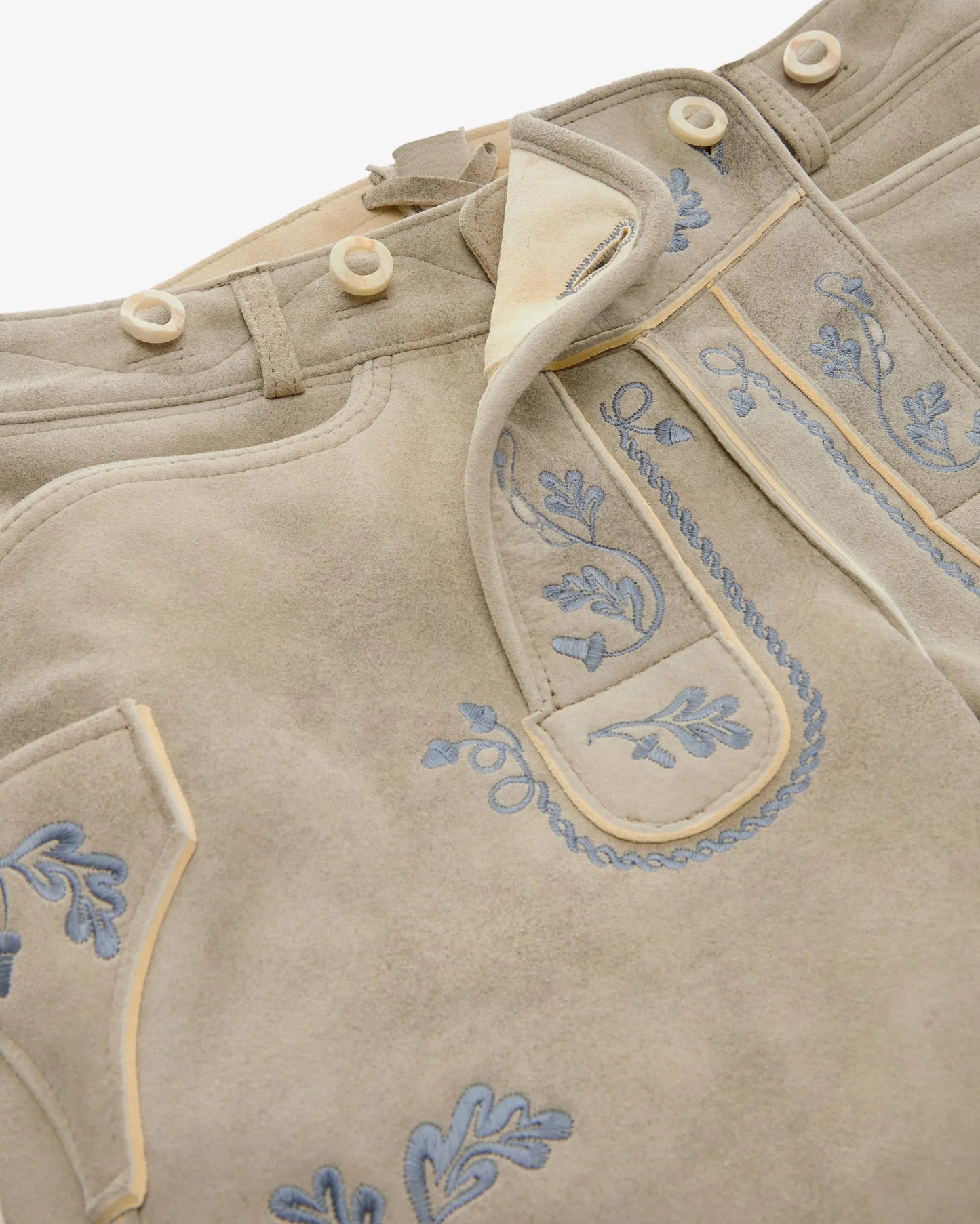 Close-up of a traditional outfit with embroidered details on a beige background