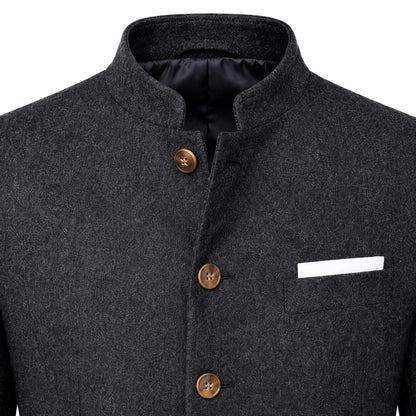 Close-up of a dark gray textured wool jacket with a mandarin collar, three brown buttons, and a white pocket square in a chest pocket.