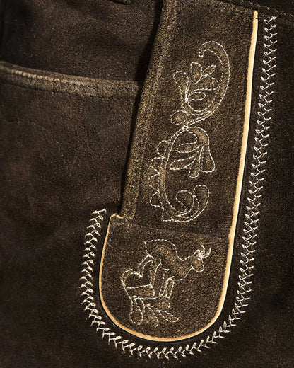 Close-up of a black leather jacket with intricate white embroidery on a dark background