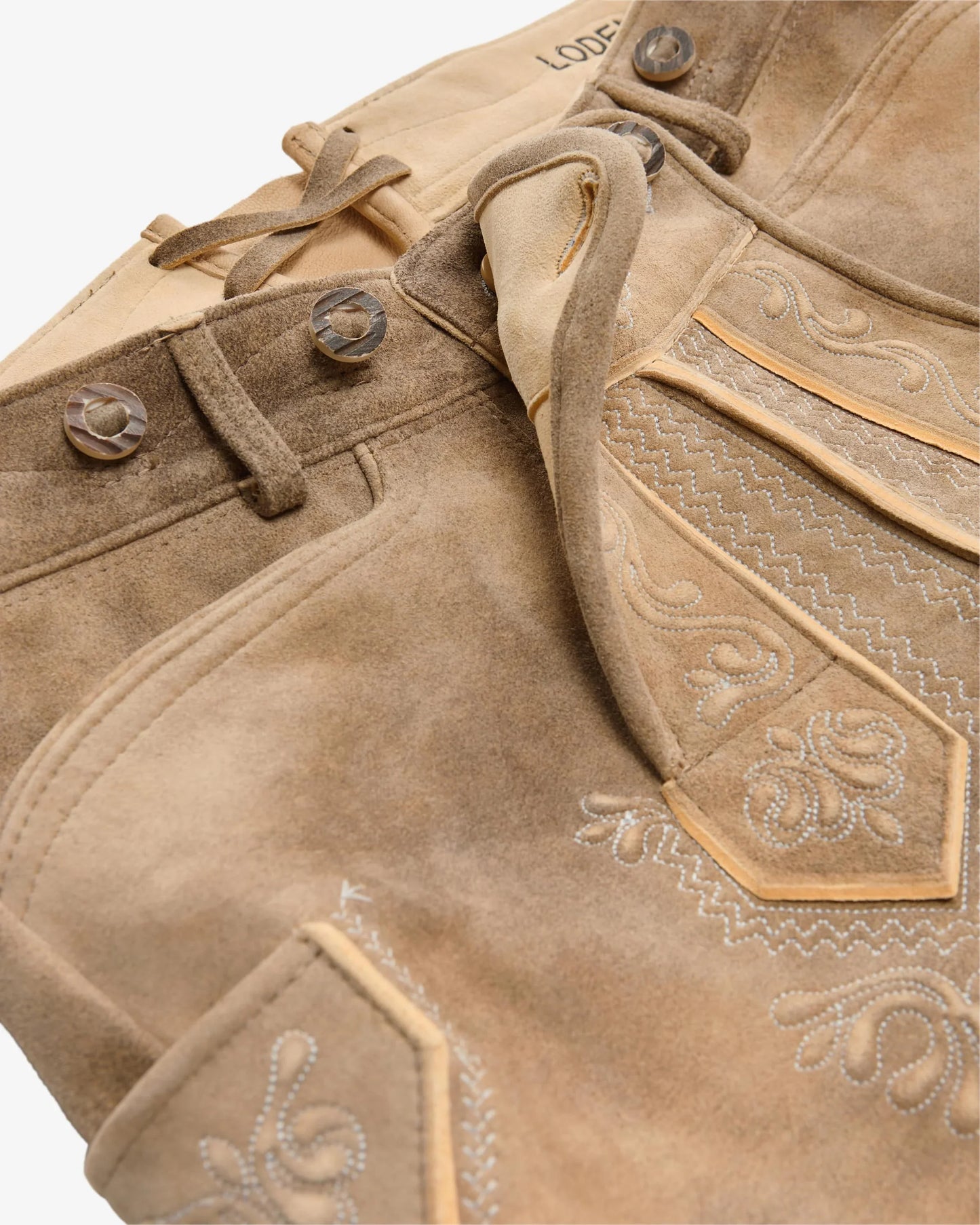 Close-up of a brown leather jacket with intricate stitching and decorative elements.