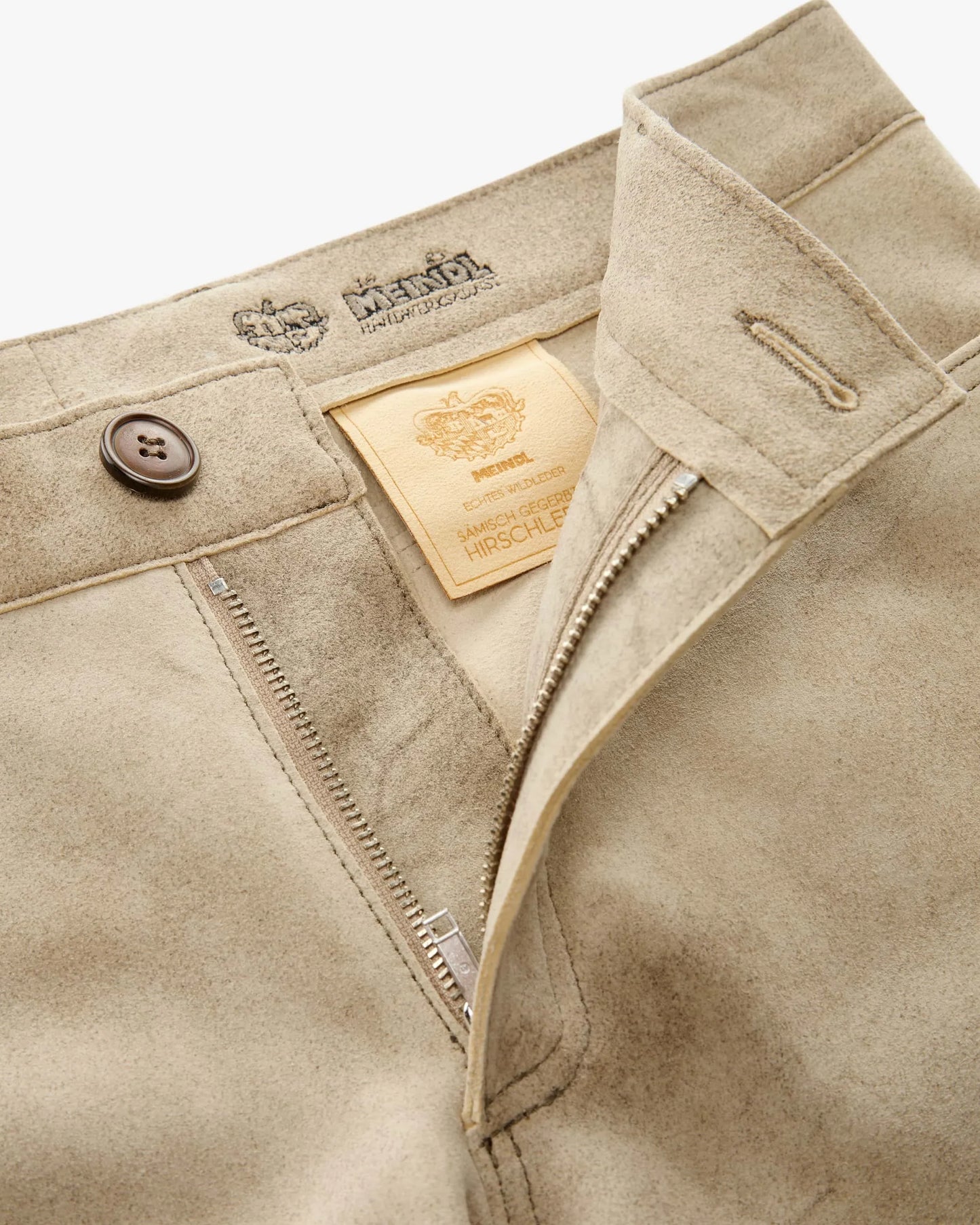 Close-up of beige pants with brand label and button details