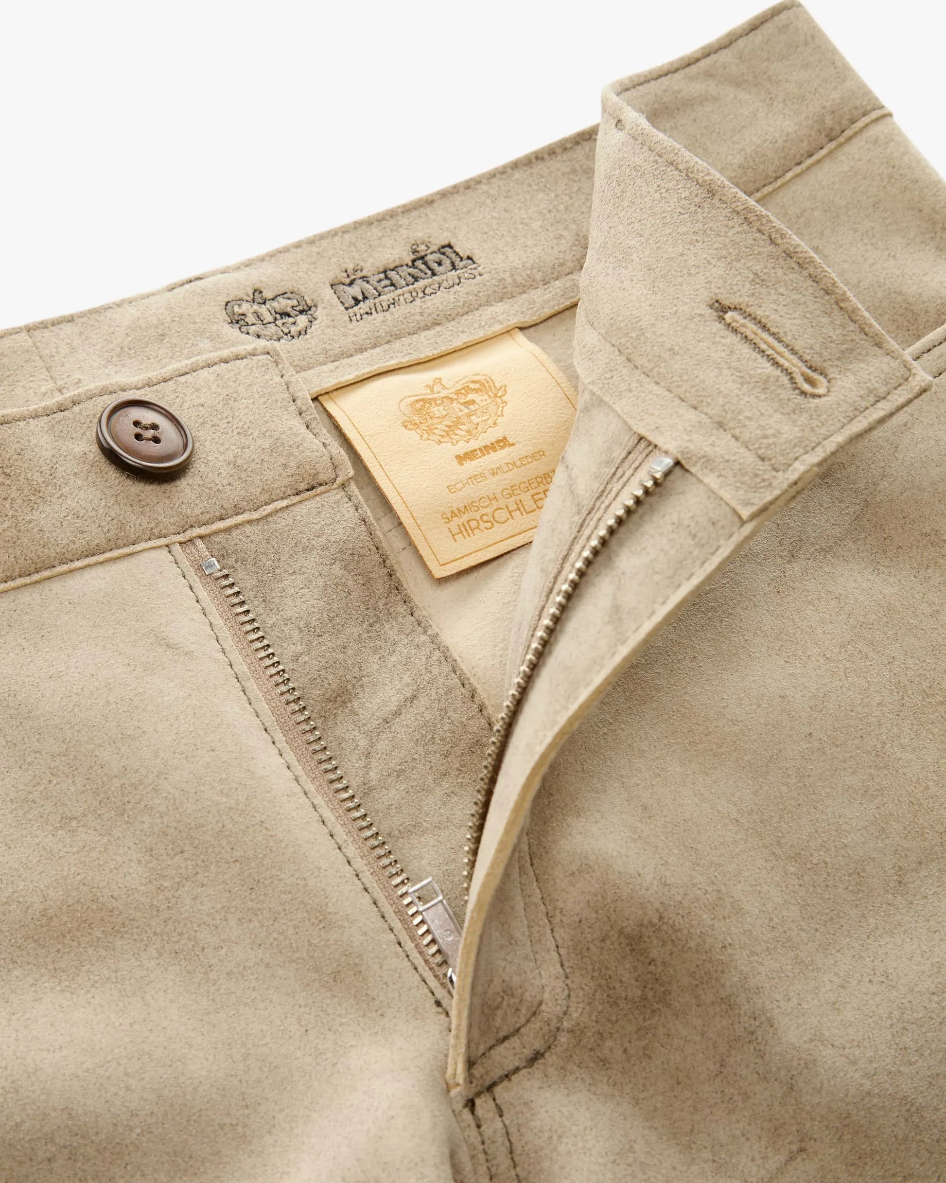 Close-up of beige pants with brand label and button details