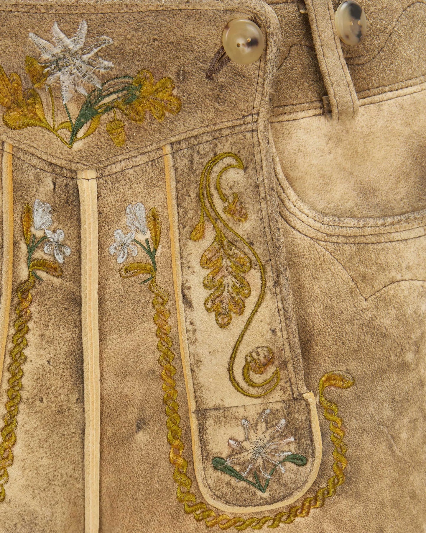 Close-up of embroidered fabric with floral patterns on a beige background