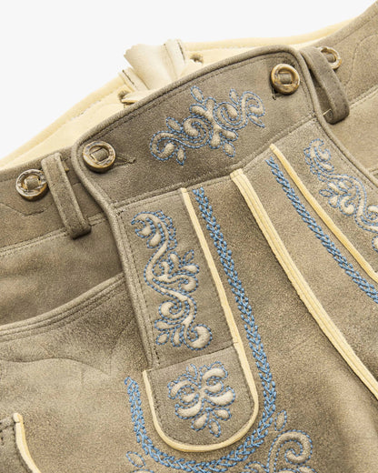 Close-up of a brown leather outfit with blue embroidery on a white background
