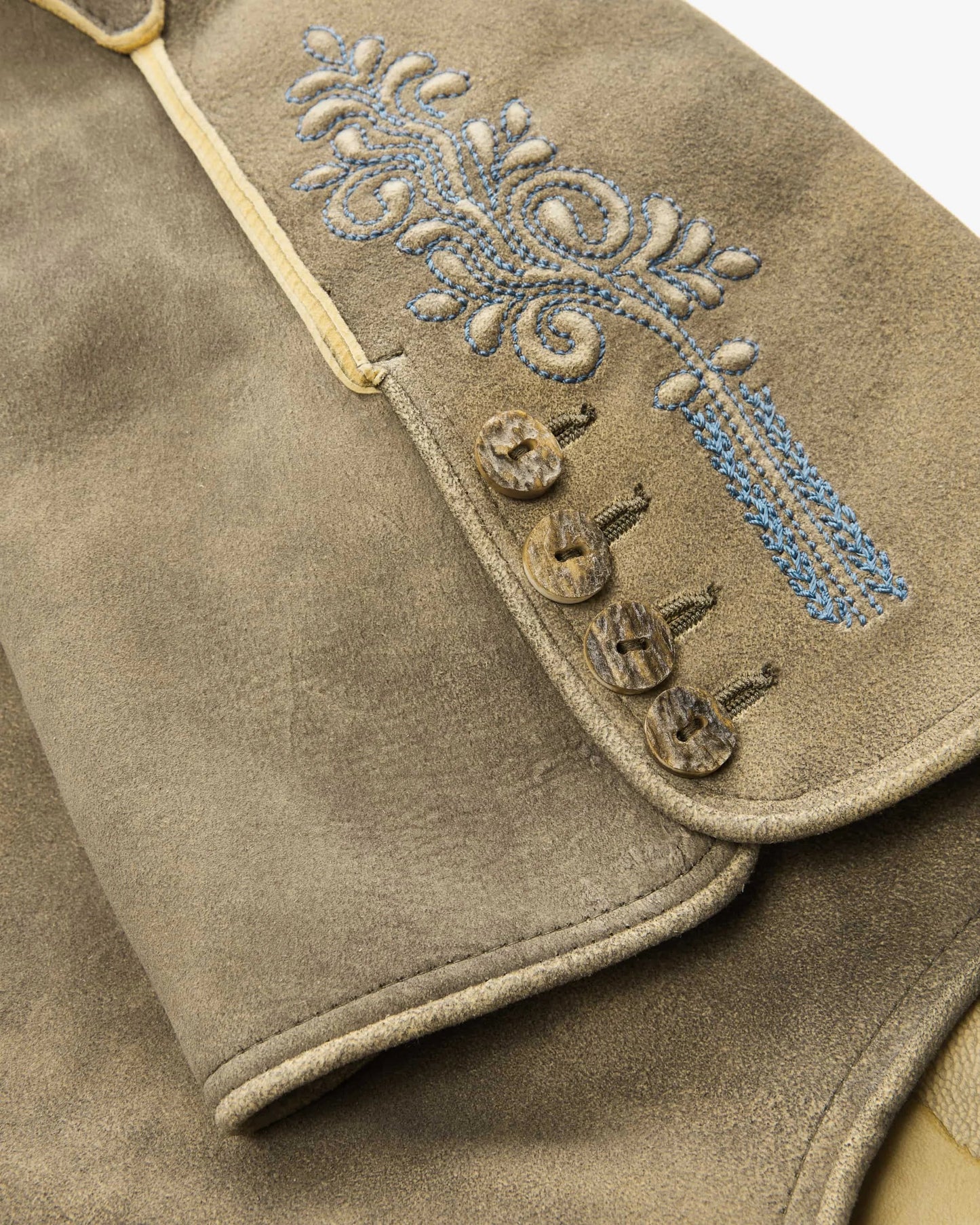 Close-up of a brown leather vest with decorative embroidery and buttons.