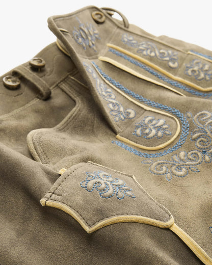 Close-up of a brown garment with blue embroidery on a white background