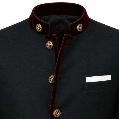 A close-up of a black traditional jacket with a contrasting deep red velvet collar and front trim, accented by gold-tone decorative buttons and a white pocket square.