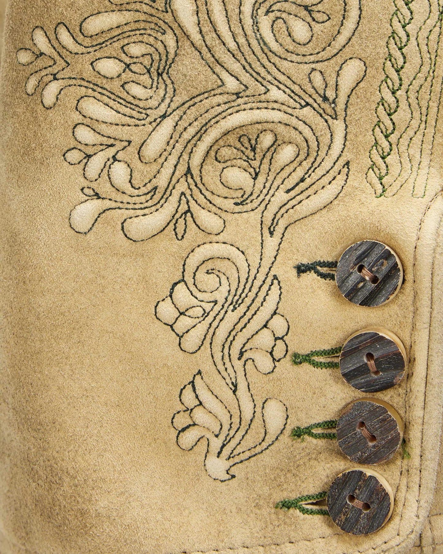 Close-up of a beige fabric with intricate embroidery and three wooden buttons.