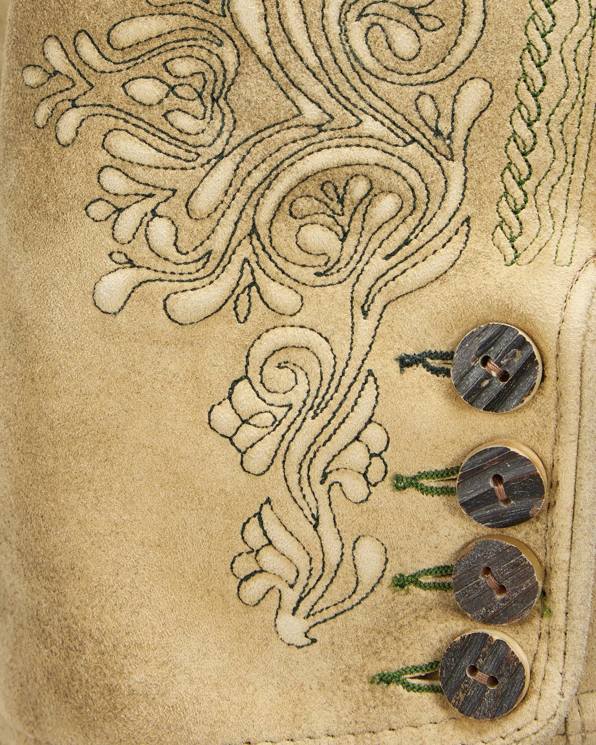 Close-up of a beige fabric with intricate embroidery and three wooden buttons.