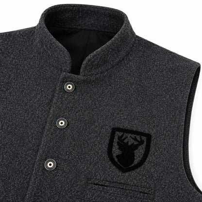 Close-up of a dark heather gray wool vest with a mandarin collar, snap-button placket, and a black embroidered shield logo patch on the chest.