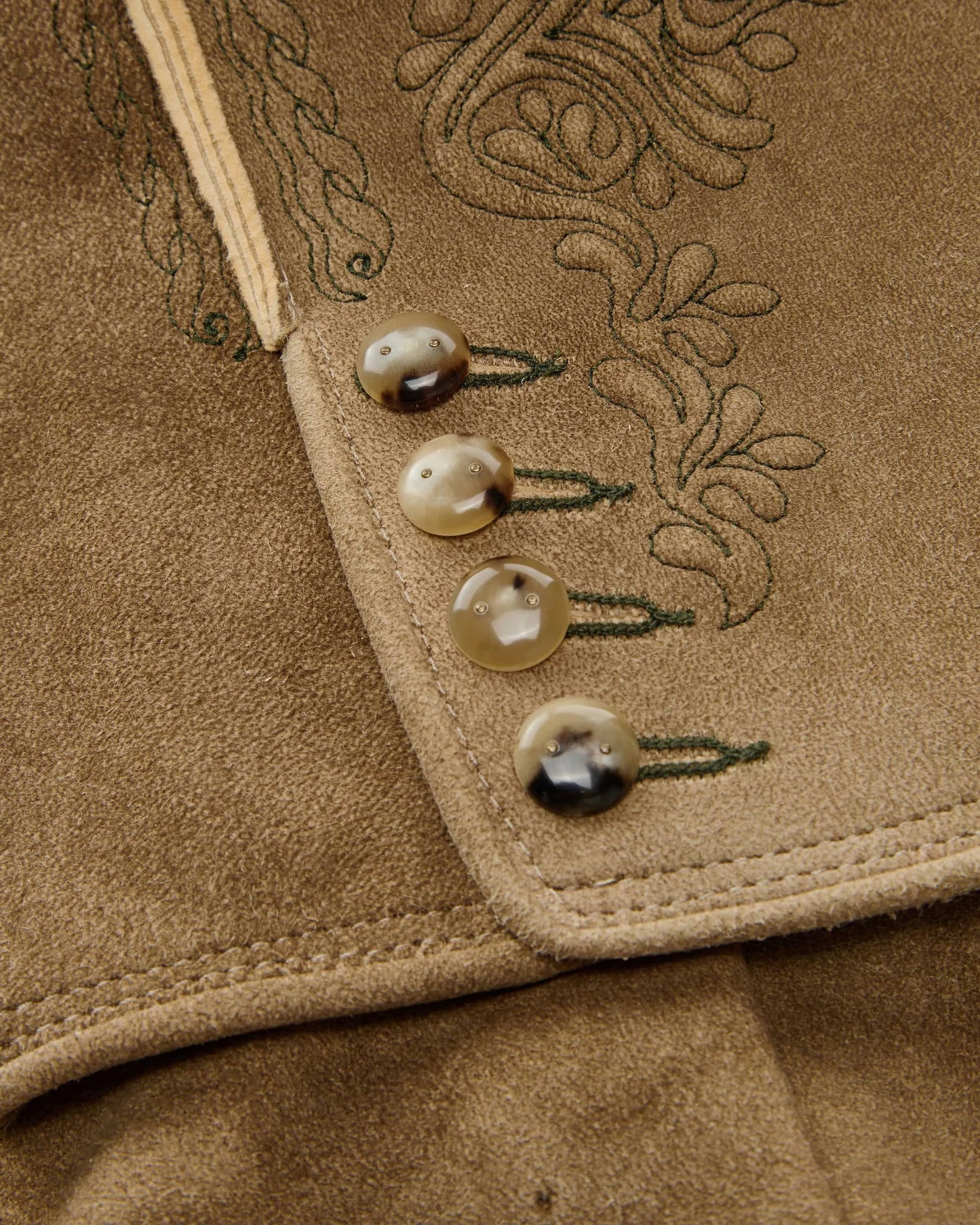 Close-up of a brown fabric with embroidered details and buttons.