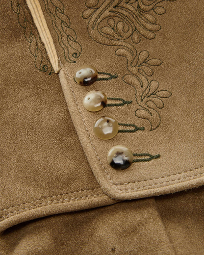Close-up of a brown fabric with embroidered details and buttons.