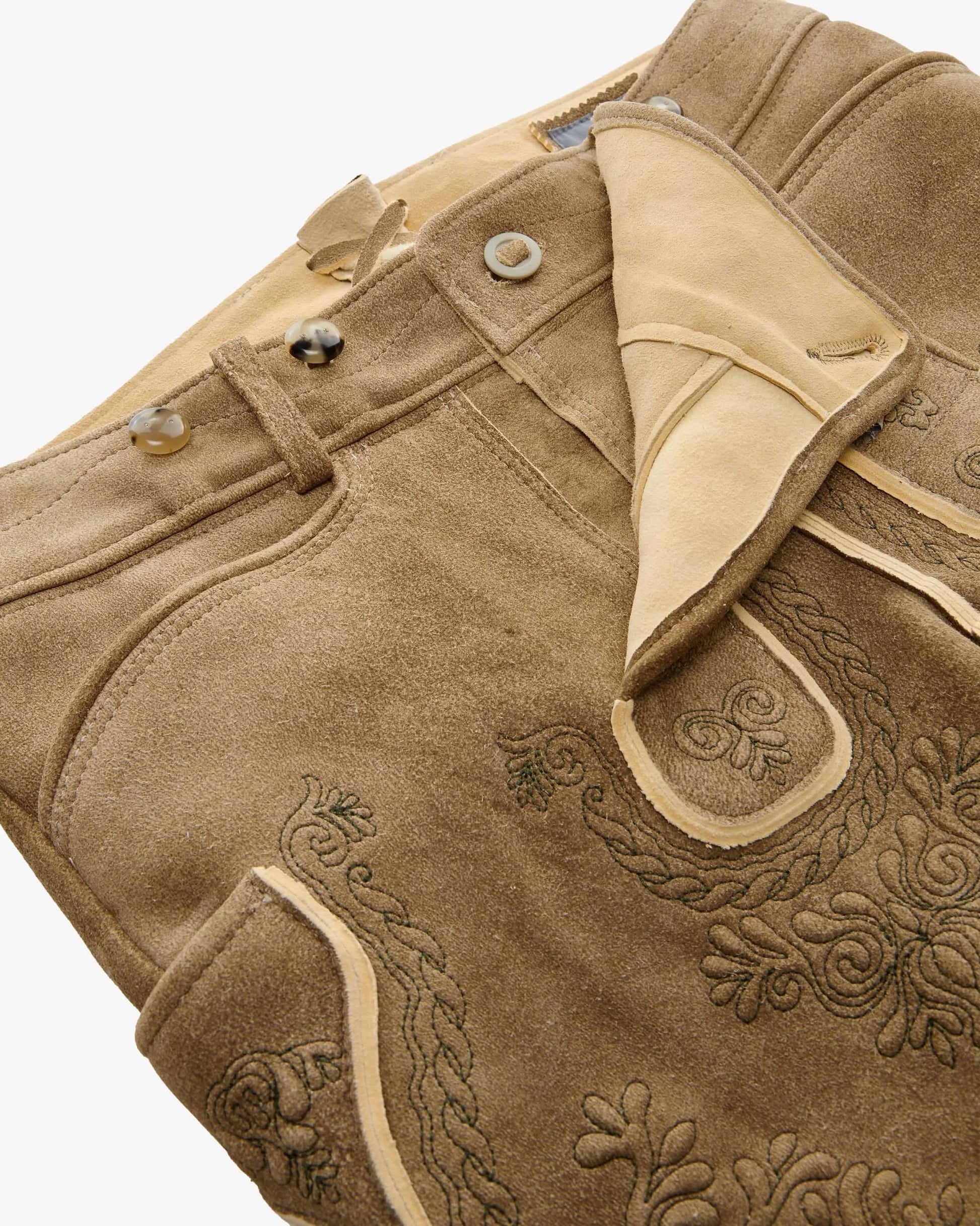 Close-up of a brown leather jacket with intricate embroidery on a white background