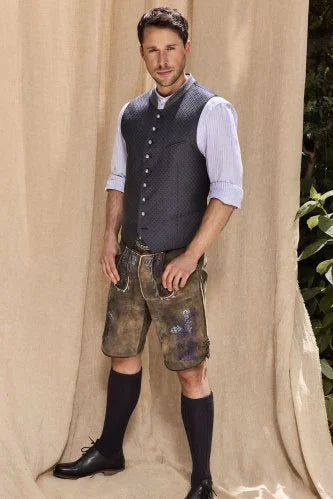 Man wearing traditional German clothing against a beige curtain background